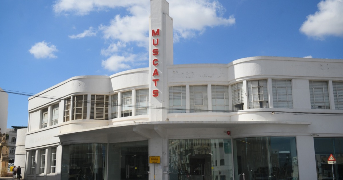 The white Streamline Moderne Muscats Motors showroom in Gżira, with rounded corners, ribbon windows and a slim vertical sign.