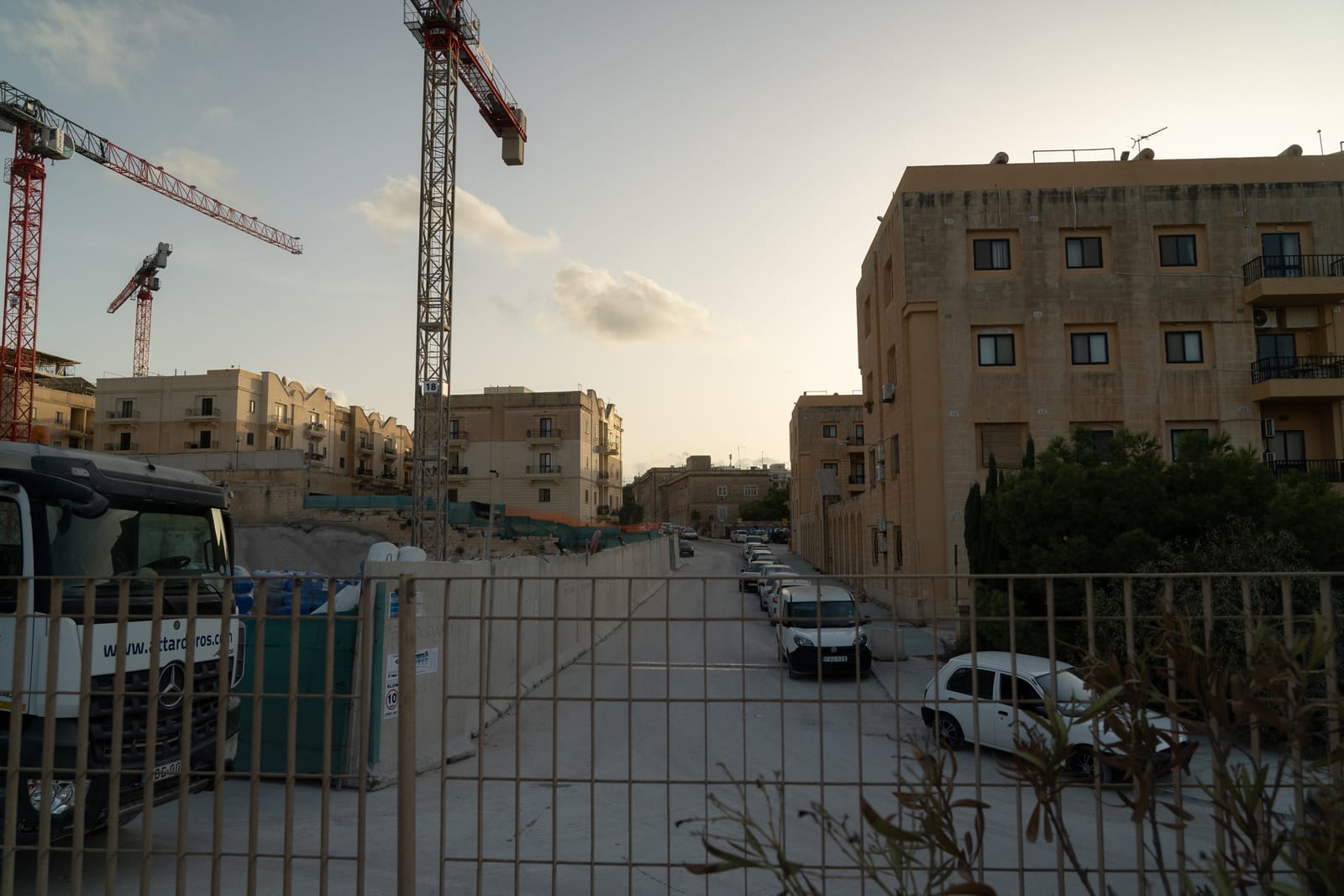 A street of low traditional Pembroke townhouses with tall construction cranes towering over the rooftops behind them