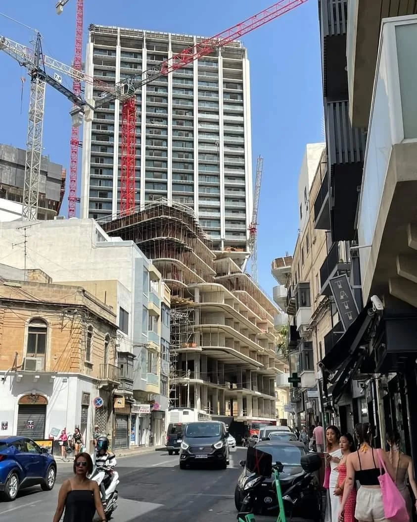 Construction towers rising over a Maltese street