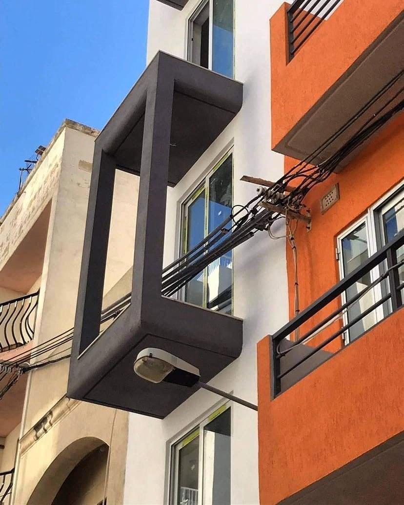 An orange block cluttered with balconies and AC units
