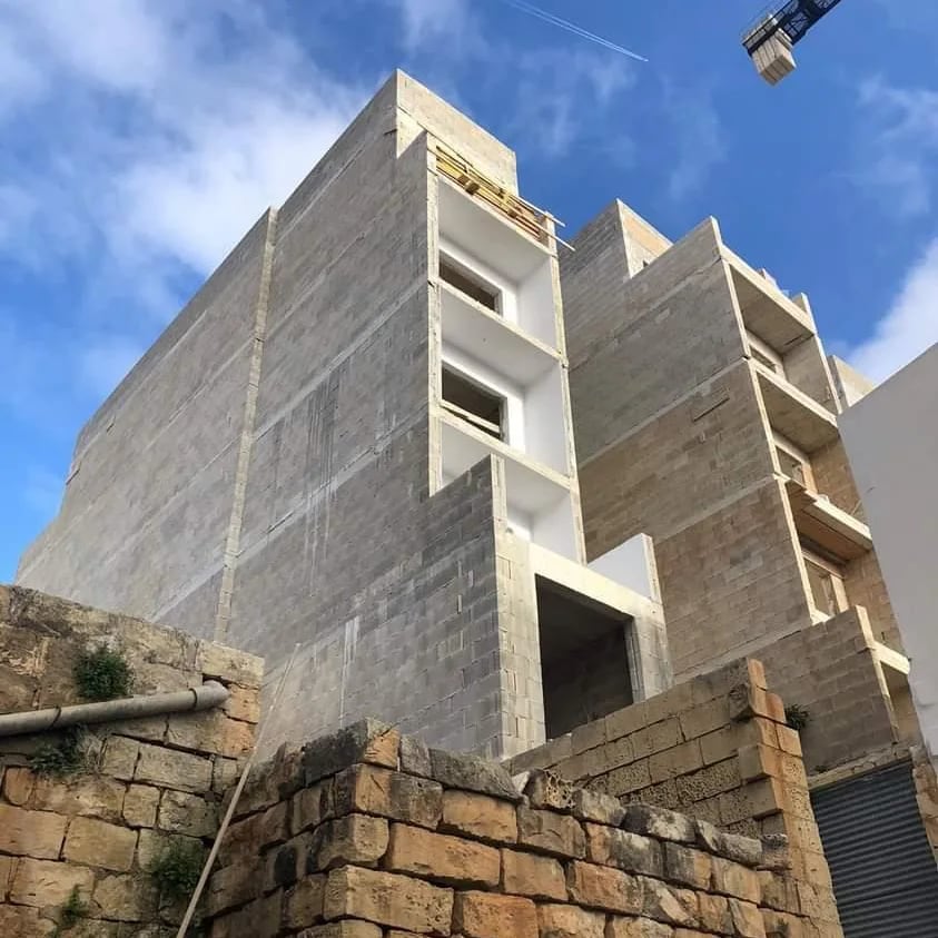 A brutalist limestone building under construction